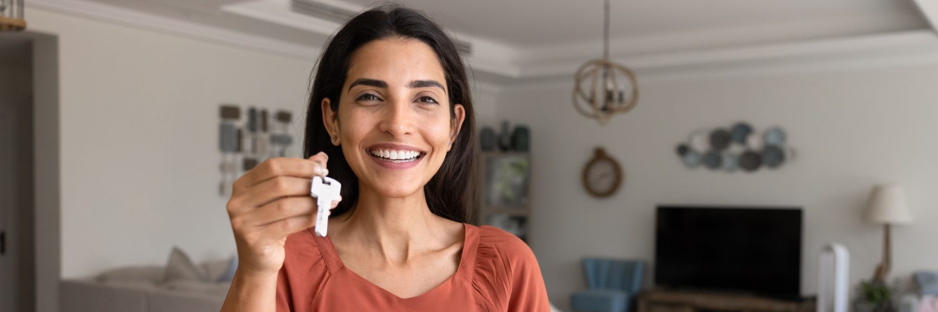 Femme souriante présentant les clés de son nouvel appartement