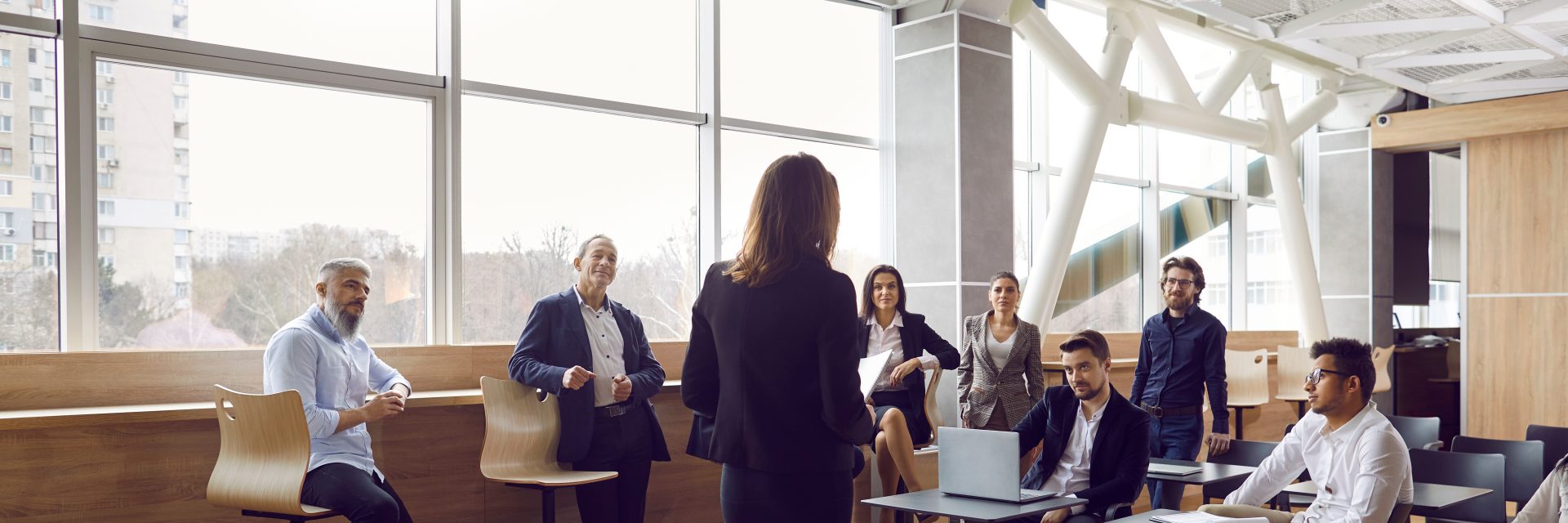 Plusieurs hommes d'affaires écoutent une dirigeante d'entreprise lors d'une réunion d'entreprise ou d'une conférence de formation.